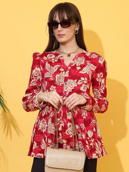Woman wearing maroon floral top with long sleeves and beige crossbody bag, yellow background