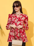Woman wearing maroon floral top with long sleeves and beige crossbody bag, yellow background