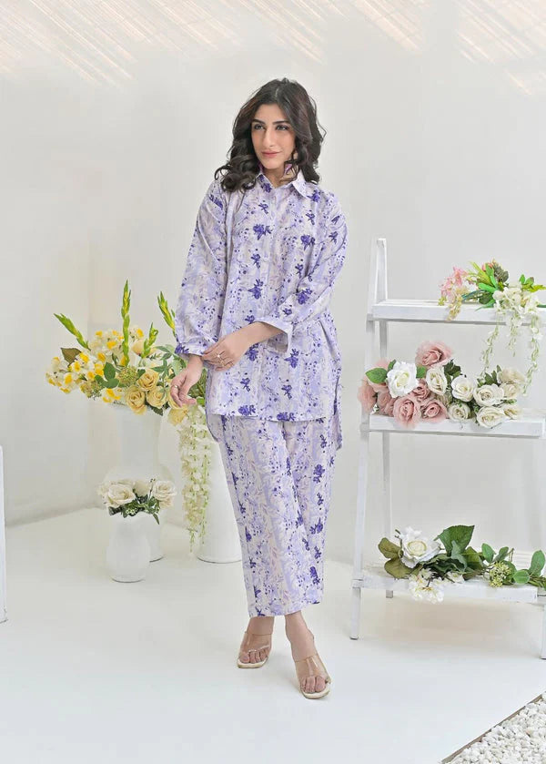 Woman wearing lilac floral two-piece outfit, standing indoors with flowers and white decor.