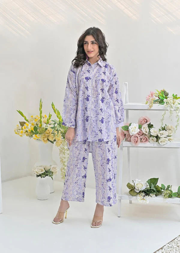 Woman wearing lavender floral pajama set, standing in a bright room with flower arrangements.