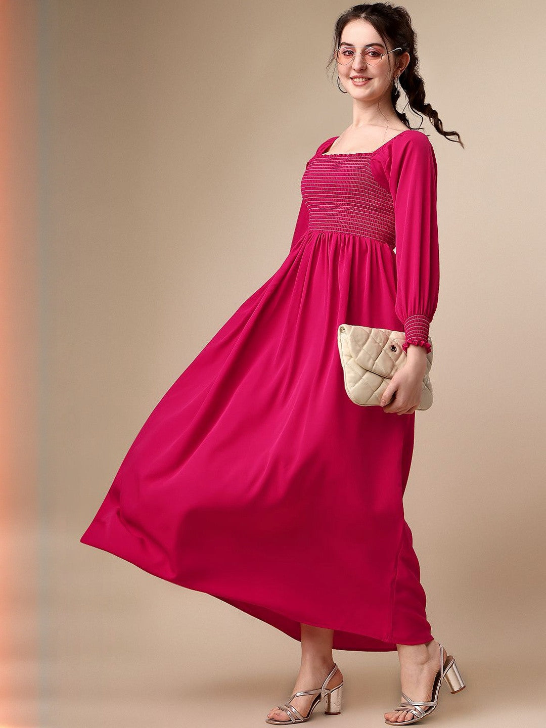 Woman in a long-sleeve hot pink maxi dress with a quilted clutch and heeled sandals