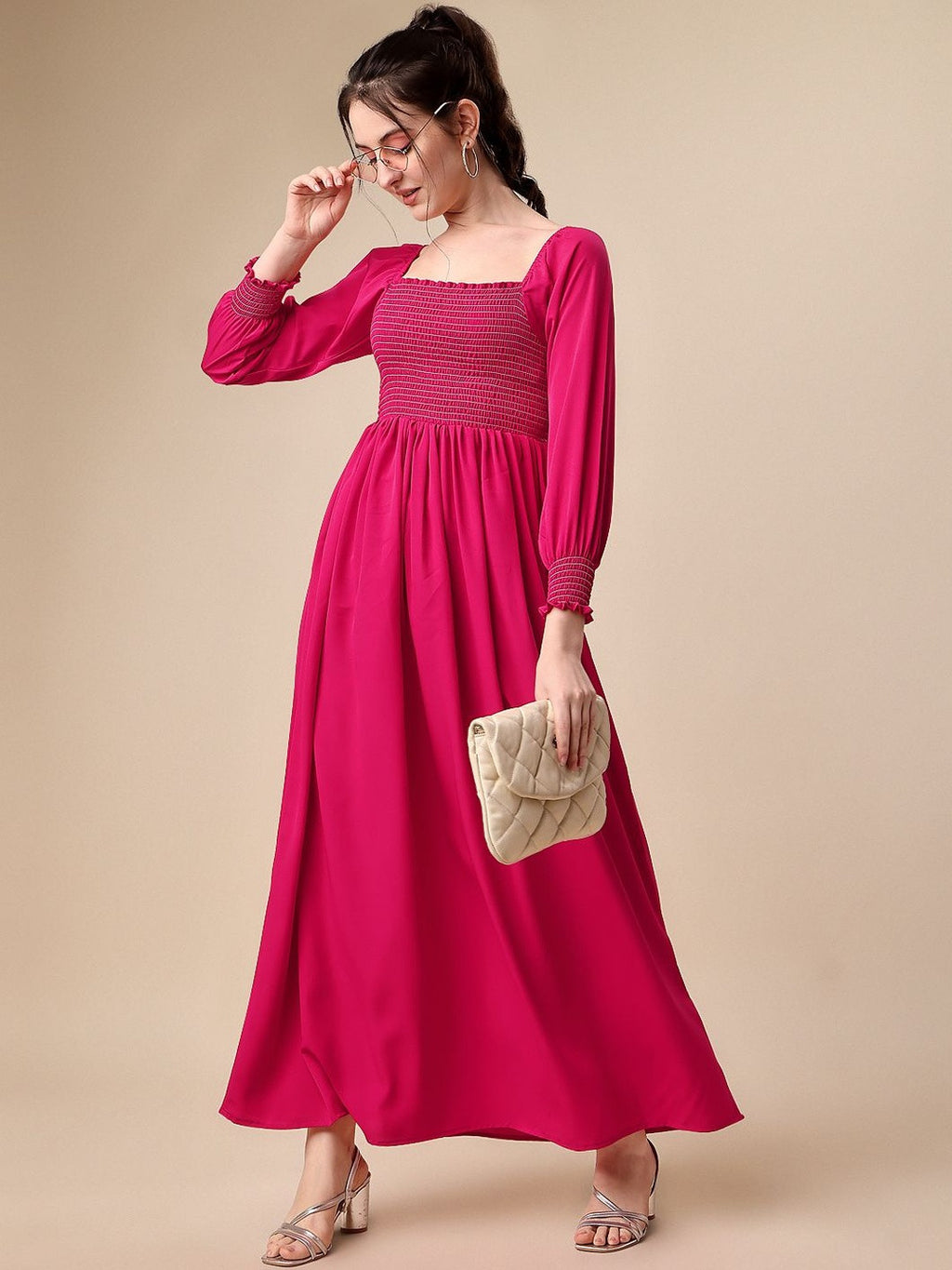Woman in long pink smocked maxi dress with square neckline, holding quilted clutch