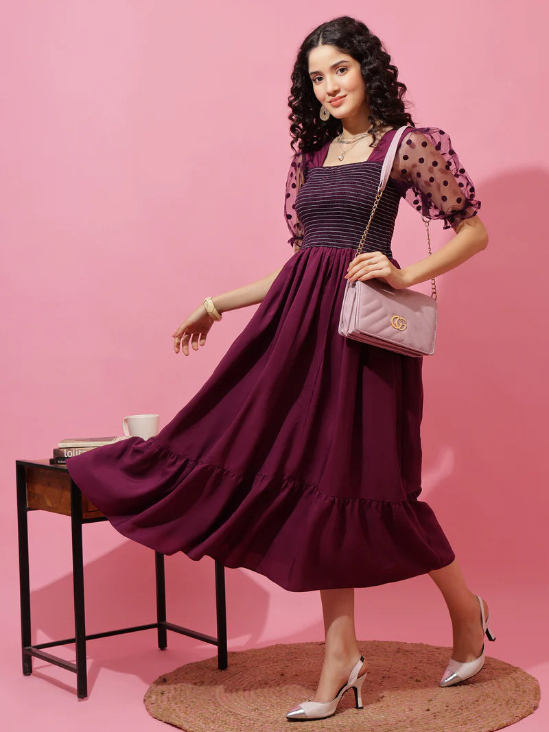 Woman in a purple midi dress with sheer polka dot puff sleeves, pink purse and heels
