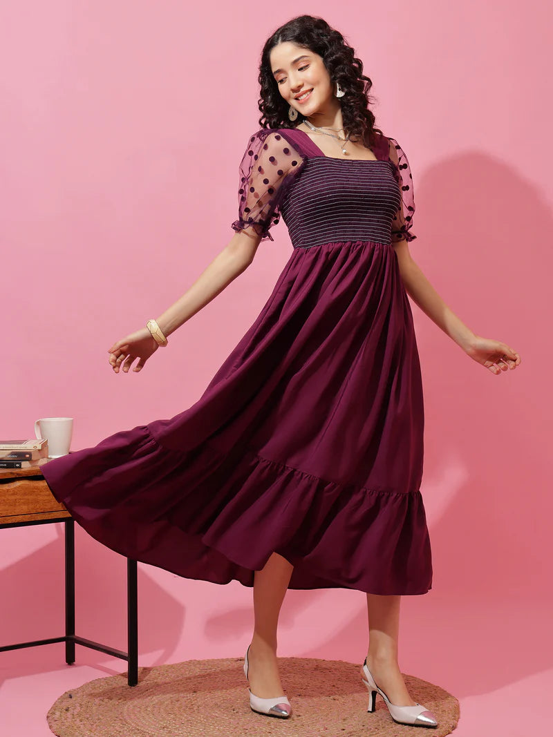 Woman wearing a purple midi dress with puffed polka dot sleeves, twirling against pink background